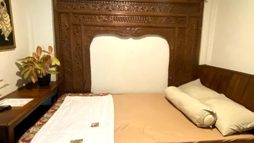 a bed with a wooden headboard in a room at Omah kayu bromo in Ngadisari
