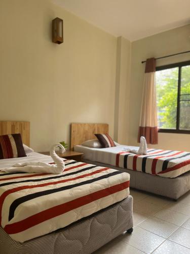 a bedroom with two beds and a window at Chat Residence Hotel in Chiang Rai