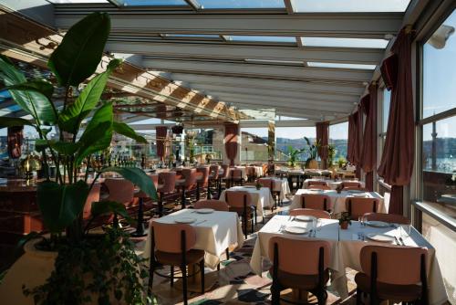 een restaurant met witte tafels, stoelen en planten bij Crowne Plaza Istanbul - Ortakoy Bosphorus, an IHG Hotel in Istanbul