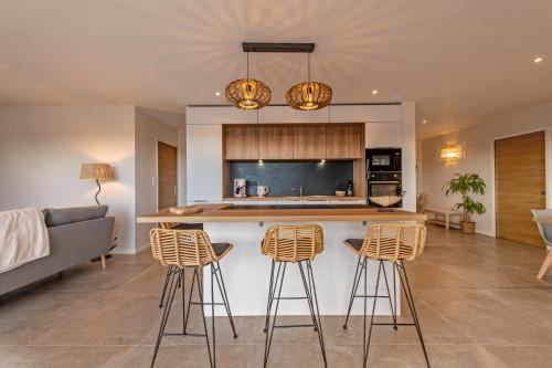 une cuisine avec un comptoir et des tabourets dans une pièce dans l'établissement Villa du Menhir 300m plage à pied, à Plouescat