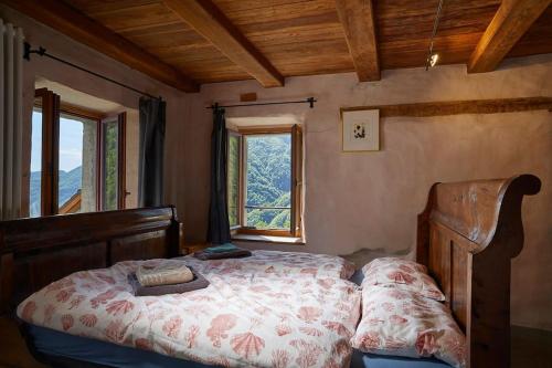 a bedroom with a bed with a large window at Wild Valley Puro Ticino 1+2 in Valle Onsernone in Crana