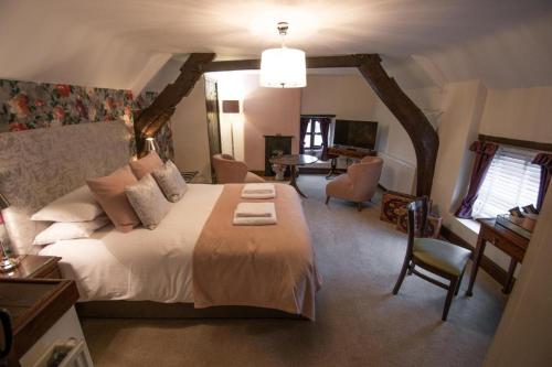 a bedroom with a large bed with a desk and a chair at The Royal George in Cottingham