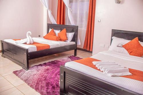 a bedroom with two beds with orange and white pillows at Hotel Wagon Wheel in Nakuru