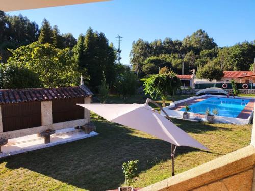 una sombrilla blanca en un patio con piscina en LA CAMELIA, en Pontevedra