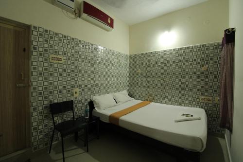 a small bedroom with a bed and a chair at Just Guest House, Chennai Airport in Chennai
