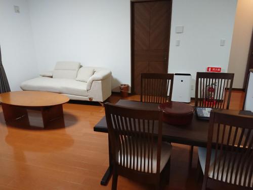 un soggiorno con tavolo, sedie e divano di 西ノ浜の宿　マリーナ萩 a Hagi