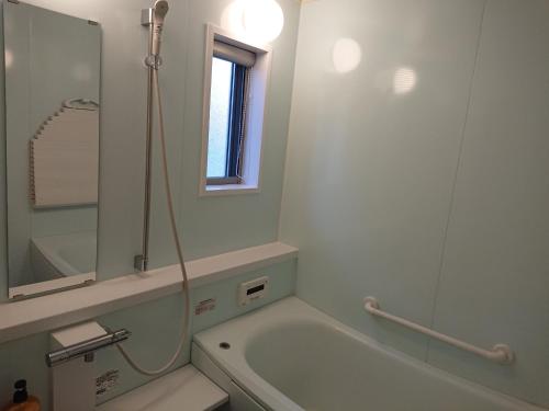 bagno con vasca, lavandino e specchio di 西ノ浜の宿　マリーナ萩 a Hagi