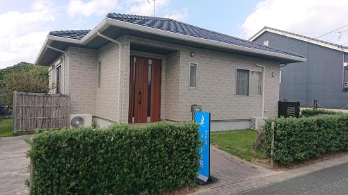 una casa con un cartel delante de ella en 西ノ浜の宿　マリーナ萩, en Hagi