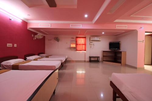 a room with four beds and a flat screen tv at Just Guest House, Chennai Airport in Chennai