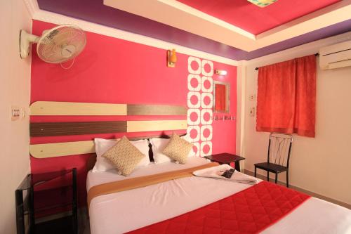 a bedroom with a bed with a red wall at Just Guest House, Chennai Airport in Chennai
