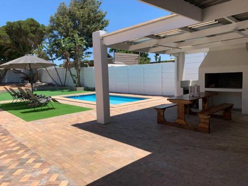 een patio met een picknicktafel en een parasol bij Villa Lamsyh- your second home in Kaapstad