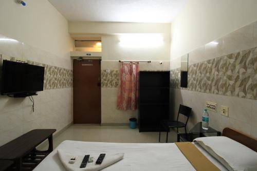 a room with a bed and a tv and a bathroom at Just Guest House, Chennai Airport in Chennai
