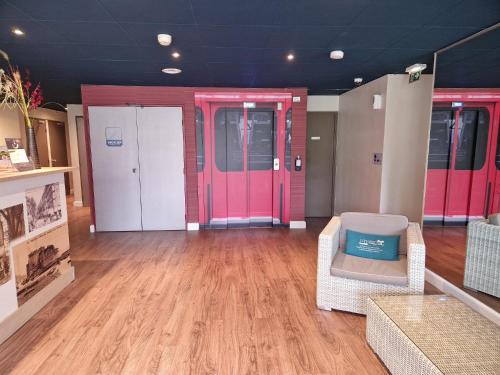 ラ・ギャルドにあるKyriad Toulon Est Hyeres La Gardeのピンクのドア、ソファ、椅子が備わる客室です。