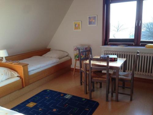 a room with a table and a bed and a table and chairs at Wohnung-Herzmuschel-im-Haus-Muschelgarten in Alkersum