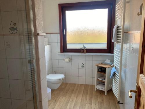 a bathroom with a toilet and a window at Wohnung-Herzmuschel-im-Haus-Muschelgarten in Alkersum