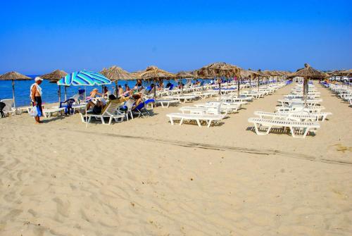 una playa con muchas sillas y sombrillas y el océano en Chalkidiki rent house, en Vergia