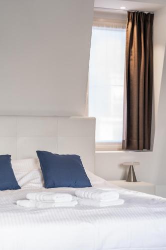 a white bed with blue pillows and a window at Maison Bruges in Bruges