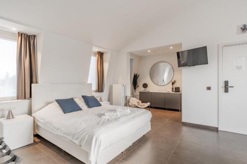 ein weißes Schlafzimmer mit einem großen weißen Bett mit blauen Kissen in der Unterkunft Maison Bruges in Brügge