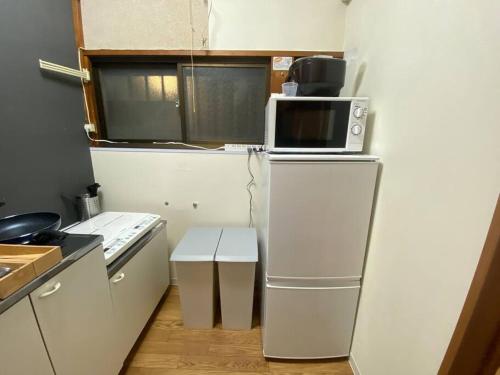 a kitchen with a microwave on top of a refrigerator at 【浅草・秋葉原・銀座・スカイツリー・東京タワー他直通！】最大8人 in Tokyo