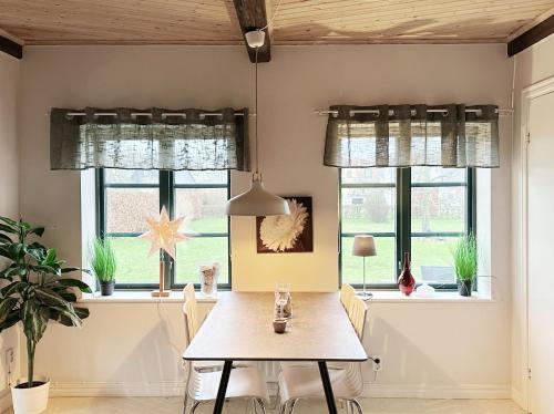a dining room with a table and chairs and windows at Kåseberga Byhus in Ystad