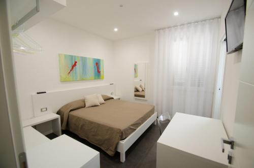 um pequeno quarto branco com uma cama e uma janela em Sea Salt em Porto Cesareo