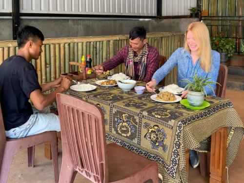 Eine Gruppe von Menschen, die an einem Tisch sitzen und Essen essen. in der Unterkunft Backpacker Hostel and Jungle Trekking in Banlung