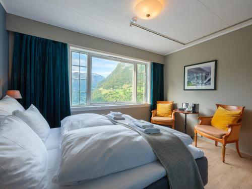 a bedroom with a bed and a large window at Hotel Utsikten - by Classic Norway Hotels in Geiranger