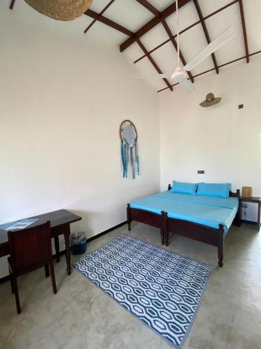 a room with a bed and a table and a rug at The Calm Palm in Hikkaduwa