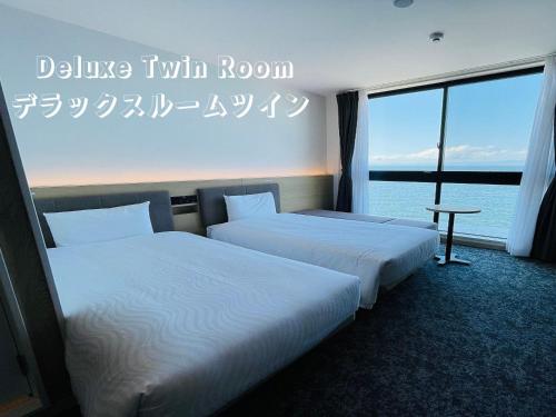 two beds in a hotel room with a view of the ocean at Henn na Hotel Kansai Airport -Natural Hot Spring Spa- in Izumi-Sano