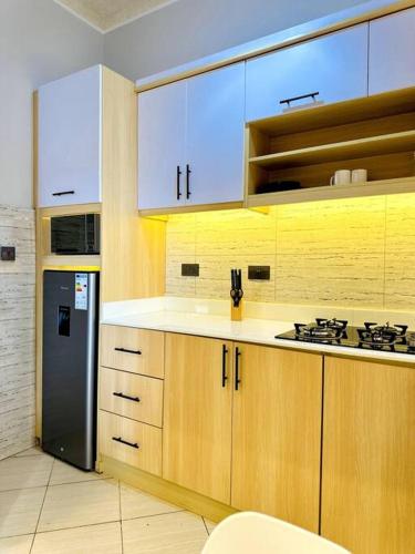 a kitchen with wooden cabinets and a black refrigerator at The Croft Homes -Kampala Buwatte in Wakiso