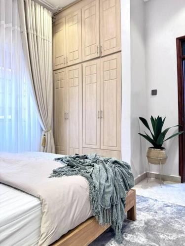 a bedroom with a large bed with a blanket on it at The Croft Homes -Kampala Buwatte in Wakiso