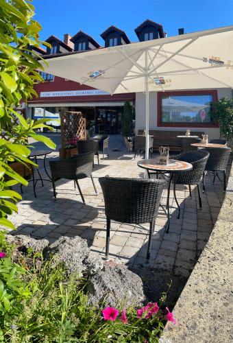 a patio with tables and chairs and an umbrella at Hotel Schwaiger in Glonn