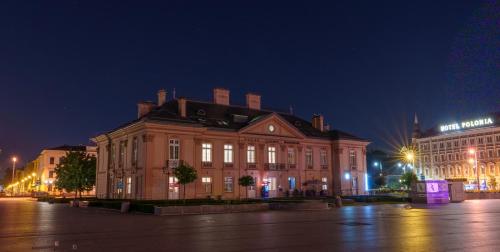 a large brick building with lights on it at night at Central Palace - LoftAffair Collection in Kraków
