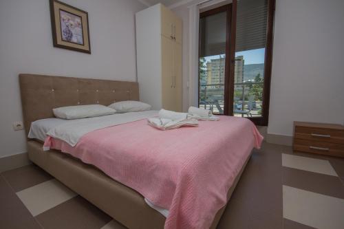 een slaapkamer met een bed met een roze deken en een raam bij Apartmani Milena in Herceg-Novi