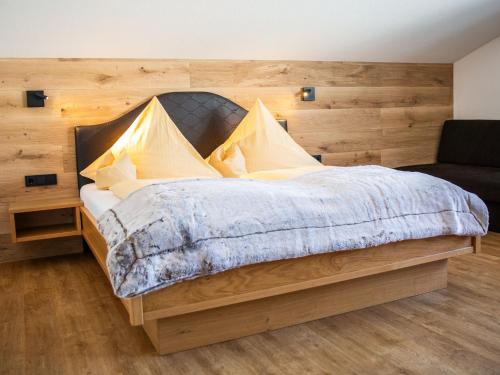 a bedroom with a large bed with a wooden wall at Landhaus Harmonie in Riezlern