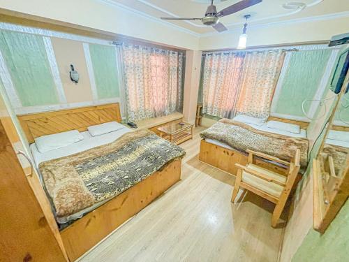 a bedroom with two beds and a chair and windows at HOTEL TOWN PALACE SRINAGAR in Srinagar