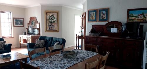 a living room with a table and a tv at Braeview Guest House in Hermanus