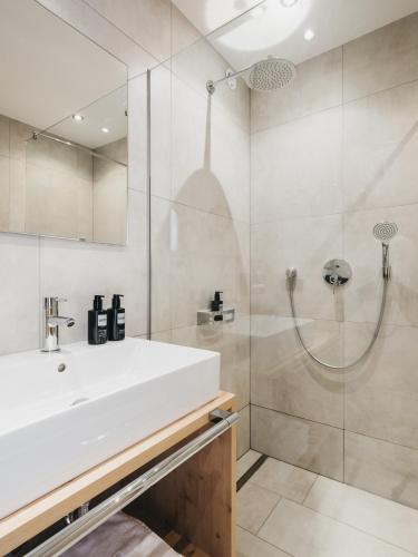 a bathroom with a white sink and a shower at VAYA Nauders inklusive Summercard Basic in Nauders