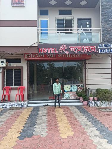 Un uomo in piedi di fronte a un hotel di HOTEL SHRI GAJANAN, a Godarpura