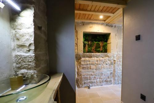 baño con lavabo de cristal y pared de piedra. en L'Hôtel Enfoncé, chambres d'hôtes, en Le Val-dʼAjol