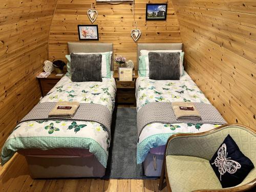 a room with two beds and a chair in it at Beautiful Twin Glamping Pod in Salisbury in Salisbury