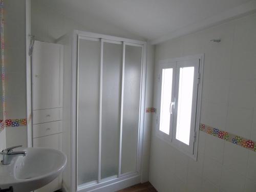 baño blanco con lavabo y ventana en Casa Sardiguera, en Montecorto