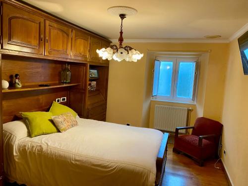 een slaapkamer met een bed en een rode stoel bij Camino a Santiago habitaciones in Villasante