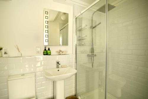 een witte badkamer met een wastafel en een douche bij 4 St Michaels House in Lyme Regis