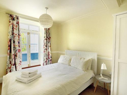 een slaapkamer met een wit bed en een raam bij 4 St Michaels House in Lyme Regis