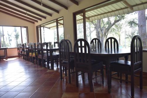 a dining room with a table and chairs and windows at River Valley Resort in Masinagudi