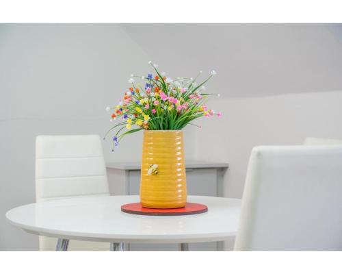 a yellow vase with flowers sitting on a table at Central Belfast Apartments Utility Street in Belfast