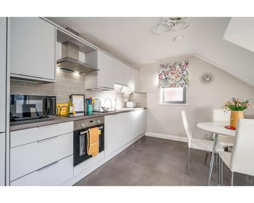 a kitchen with white cabinets and a table in it at Central Belfast Apartments Utility Street in Belfast