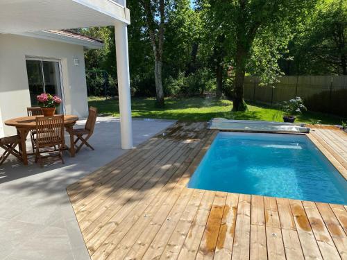 - une piscine avec une terrasse en bois et une table dans l'établissement Détente piscine à 150m de la plage à Arès, à Arès