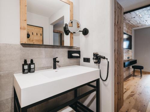 a bathroom with a white sink and a mirror at VAYA Nauders inklusive Summercard Basic in Nauders